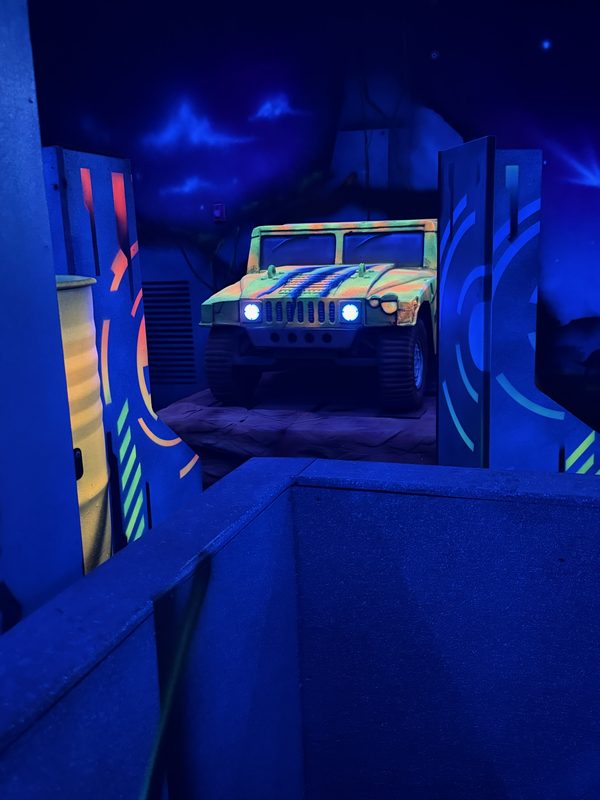 Glowing bunkers and a painted military jeep mural on the back wall of the arena