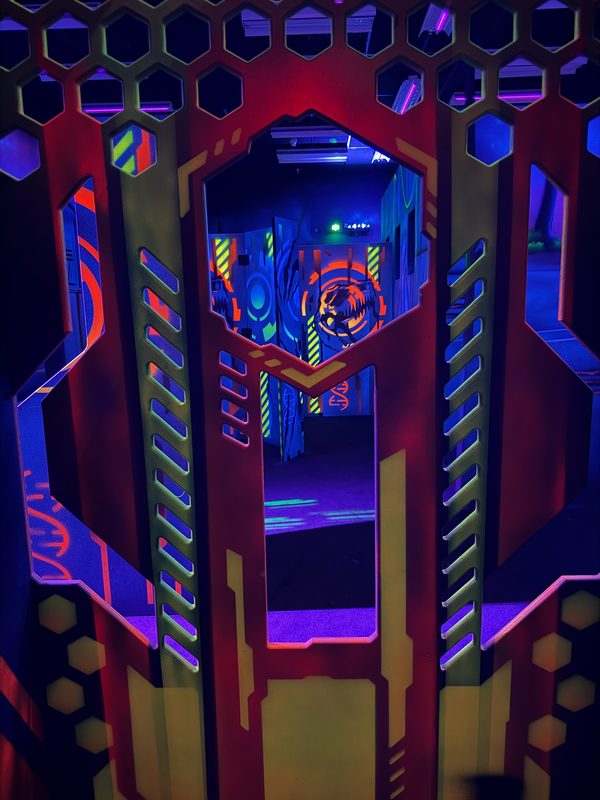 Looking through a hex-panel bunker window at the glowing arena beyond