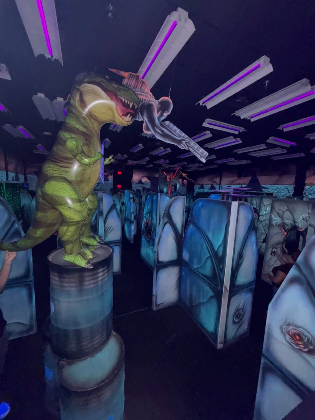 Tye the T-Rex perched on a barrel in the old blacklit arena